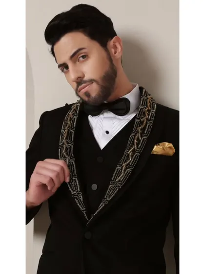 A detailed view of the Gilded Onyx Majesty tuxedo's lapel. The bold black and gold handcrafted pattern creates a symphony of dark and luminous sophistication, making it a true statement of strength and elegance.