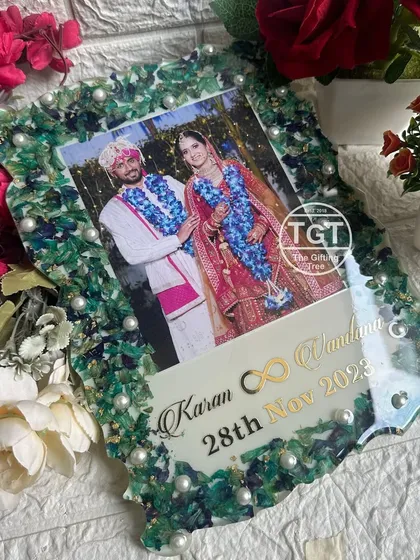 A 9x12 inch resin tabletop frame with a unique green and blue floral border made from a preserved varmala. The couple's photo, names, and date are featured prominently.