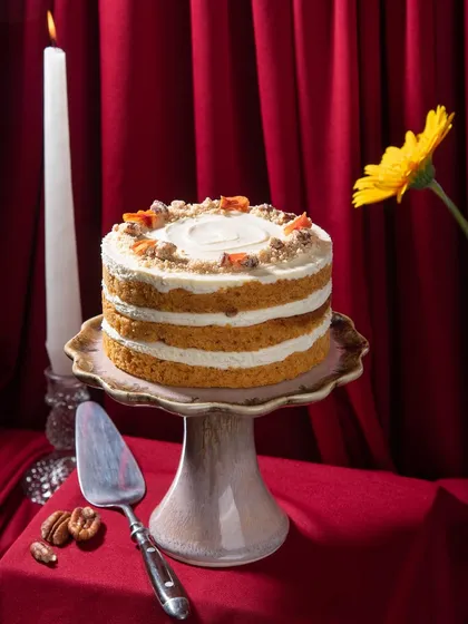 A full view of the Carrot Cake, set against a warm, candlelit background. It’s a perfect example of a comforting dessert that’s also elegant enough for any celebration.