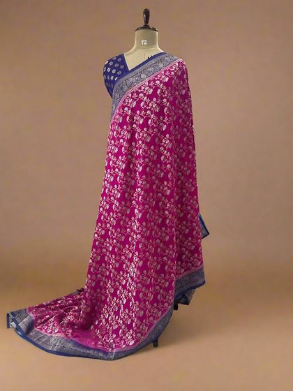 A rani pink soft crepe saree with a full silver floral jaal and a blue border.