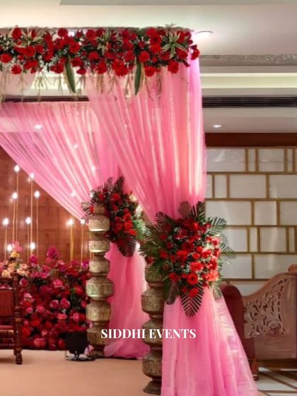 Another perspective of the enchanting red and pink mandap, highlighting the layers of floral arrangements and the soft, romantic drapery.