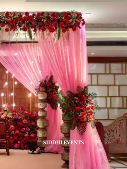 Another perspective of the enchanting red and pink mandap, highlighting the layers of floral arrangements and the soft, romantic drapery.