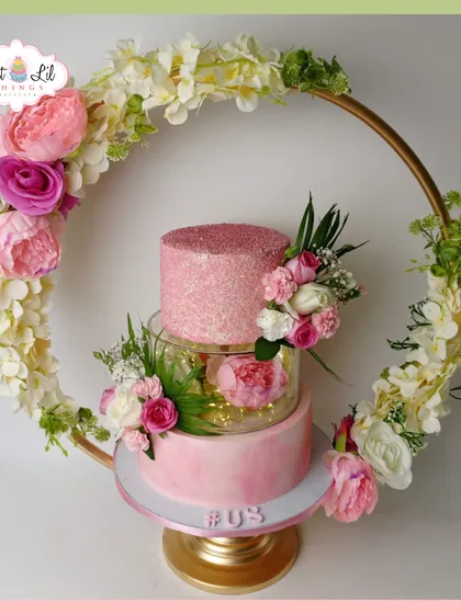 This is one of my favorite creations, a stunning pink tiered cake framed by a floral hoop. It combines modern design with classic elegance, featuring a sparkling top tier, a translucent separator with fairy lights, and a cascade of handmade sugar flowers, making it a true centerpiece for a wedding or a grand celebration.
