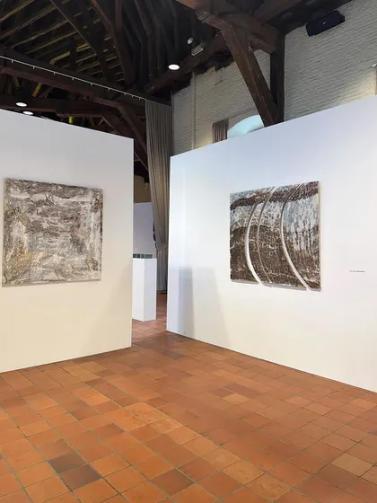 An art exhibition inside a historic building with exposed wooden ceiling beams. The juxtaposition of contemporary art against a heritage backdrop shows how old spaces can serve as dynamic settings for modern culture.