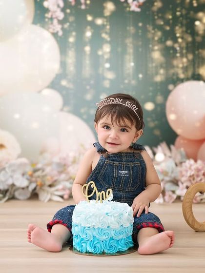 A classic first birthday portrait before the cake smash begins. This setup features a beautiful pastel balloon arch and soft lighting to create a dreamy atmosphere.