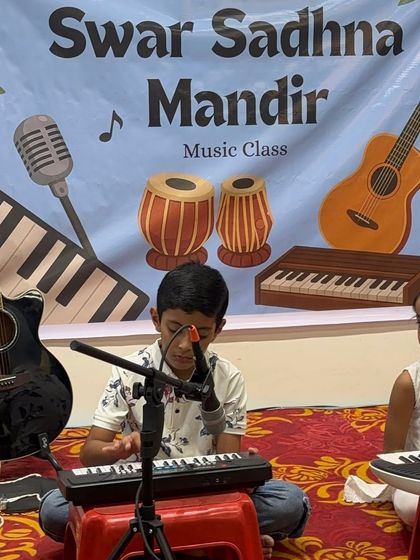 A young boy sings into the microphone while playing his keyboard. We encourage students to explore both instrumental and vocal skills, helping them become well-rounded musicians.