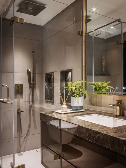 A close-up of the guest bathroom vanity highlights the rich veining of the brown marble countertop. The clean lines, integrated sink, and simple greenery create a look that is both modern and timelessly elegant.