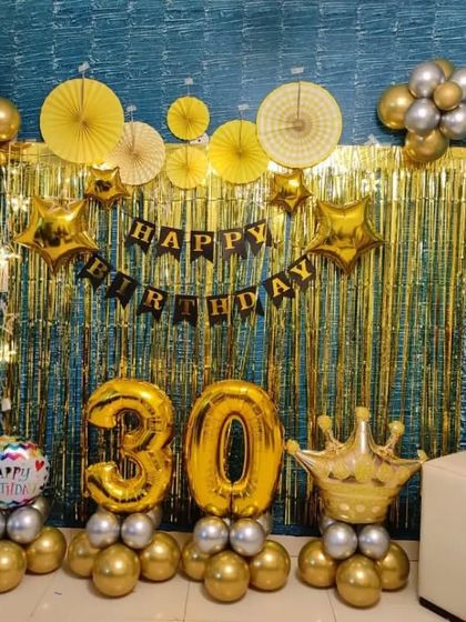 A royal-themed 30th birthday in gold and black, featuring a crown foil balloon and number balloons.