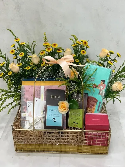 A golden wire basket filled with gourmet treats and a beautiful arrangement of yellow roses and wildflowers for Mother's Day.