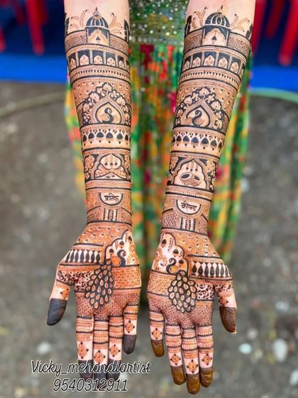 A beautiful, symmetrical design featuring peacocks and architectural domes. The names of the couple, 'Shubh' and 'Jeevan', are elegantly written on the forearms.