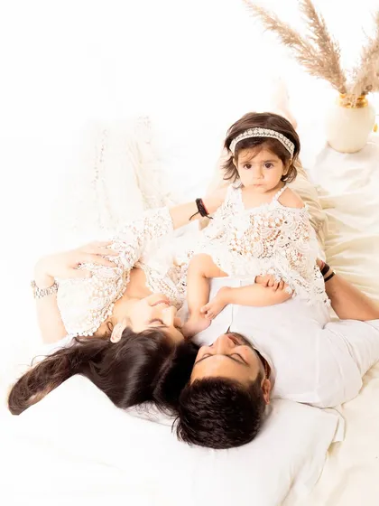 An artistic shot of a family lying down together, with their daughter positioned between them. This perspective offers a unique and intimate view of family connection.