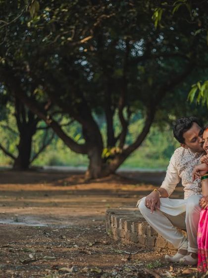 A couple shares a quiet, intimate moment under the shade of mango trees. We love using natural settings to create authentic and romantic portraits.