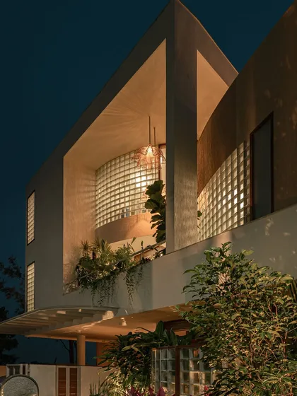 This night view shows how the integrated lighting and plants turn the home's facade into a beacon. The greenery on the balcony is highlighted, adding depth and life to the architecture.