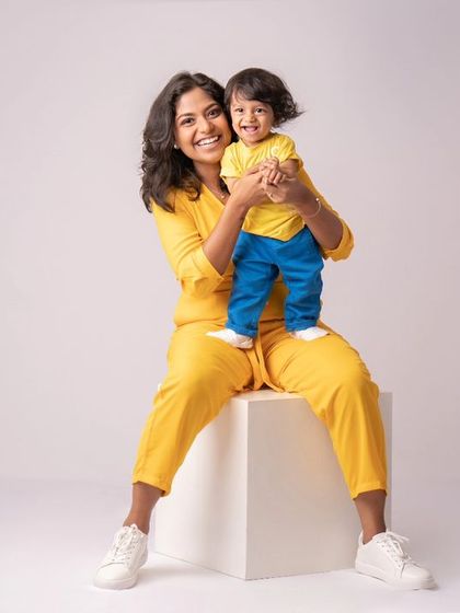 A mother and her son sharing a moment of pure sunshine. Their coordinated yellow outfits and bright smiles make this a wonderfully happy and vibrant studio portrait.