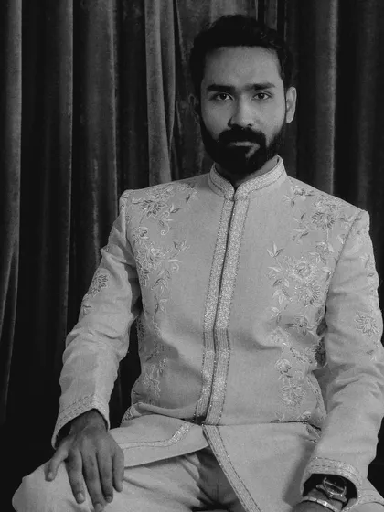 A classic black and white portrait of the groom, seated. His direct gaze and sharp attire create a powerful and timeless image.