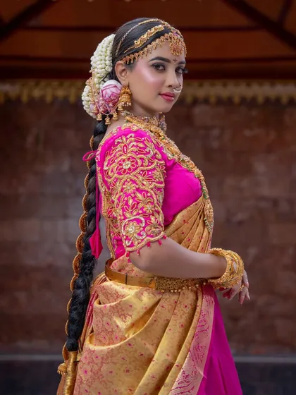 A view of the back, showcasing a long, thick traditional braid adorned with flowers. This is a classic hairstyle for South Indian brides.