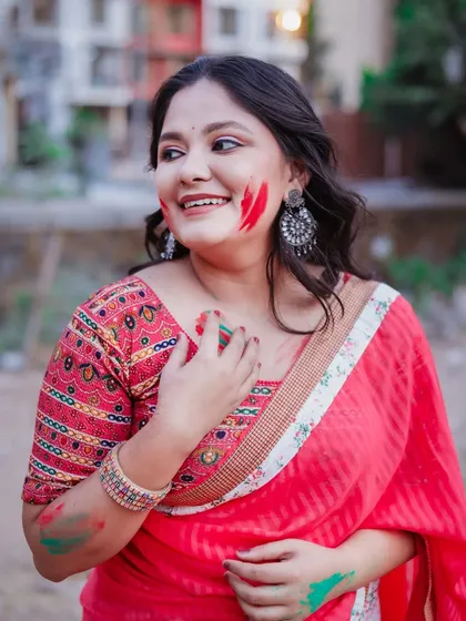 A candid shot from a Holi celebration. The model's smile and the natural outdoor setting give this photo an authentic and happy vibe.