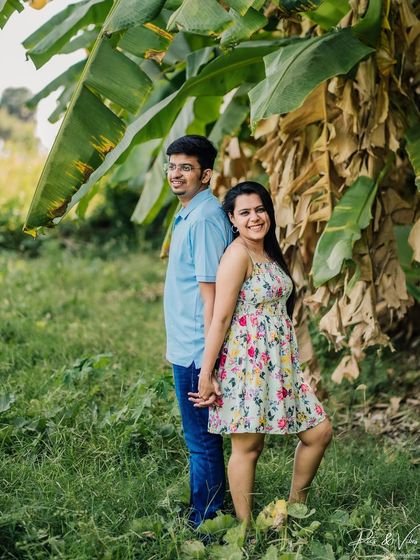 A playful back-to-back pose in a beautiful green setting, capturing the fun and relaxed vibe of the couple.