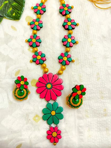 This long floral necklace features a striking combination of magenta and green. The bold colors make this a true statement piece.