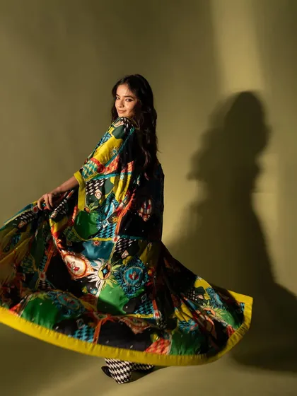 A dynamic shot of Anushka Sen, capturing the movement of her colorful, flowing cape. This adds energy and a sense of playfulness to the fashion portrait.