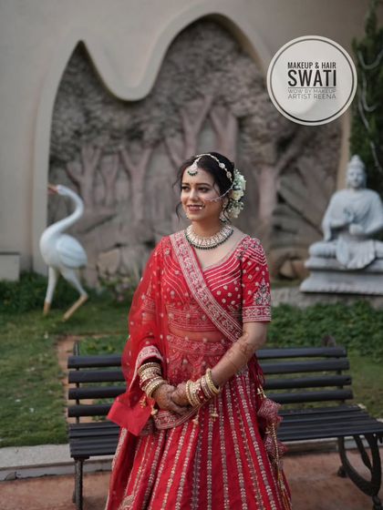 A full view of Amruta's wedding look. The outdoor setting beautifully highlights her red lehenga and the classic, elegant styling by Swati.
