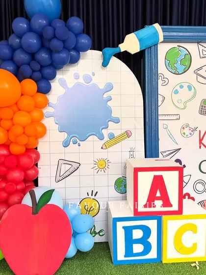 Celebrating the little graduates. For this kindergarten graduation, we created a fun, school-themed photo corner with ABC blocks, a giant apple prop, and a backdrop filled with educational doodles to mark this proud milestone.