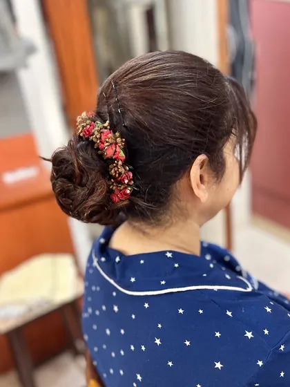 A messy bun created from the client's own hair, decorated with a beautiful red and gold hair accessory.
