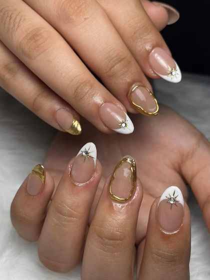 A white and gold chrome design with starburst and gem accents. This is another beautiful example of celestial-themed nail art.