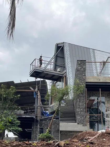 Our Karjat Residence is a house taking shape within the forest. This early construction view shows the bold geometry of a cantilevered deck reaching out into the canopy, establishing the building's intimate relationship with the surrounding nature from the very beginning.