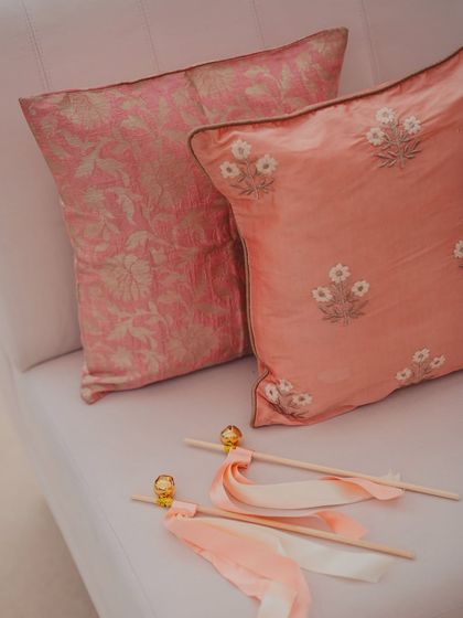 Custom cushions and delicate ribbon wands for guests, small details that contribute to the overall color story and interactive experience of the wedding.