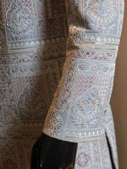 A close-up of the sleeve of our pastel-hued sherwani. You can see the fine threadwork and subtle sequin details that are woven into the geometric patterns, a testament to the skill of our artisans.