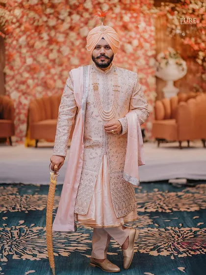 A full-length portrait of the groom on his wedding day. His royal posture, traditional sherwani, and kirpan create a powerful and elegant image.
