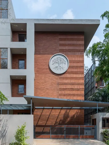 The facade of this Bengaluru apartment building showcases our approach to modern Indian architecture. The intricate exposed brickwork and custom tree-of-life emblem are a testament to our focus on craftsmanship and creating buildings with a unique identity.