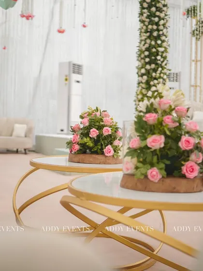 A comfortable and stylish lounge area for the Nikah celebration. The setup includes modern gold-accented tables with pink rose centerpieces, providing an elegant space for guests to relax.