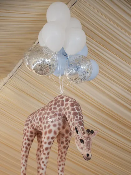 A giraffe prop appears to be lifted by a bunch of balloons, adding a touch of whimsy.