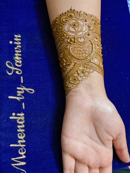 A close-up of the cuff of an engagement design. The pattern features a beautiful rose and peacock motif.