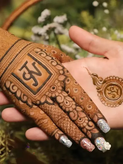 A close-up of a personalized design with the initials "JV". The groom's hand has a small matching motif, a popular trend for couples.