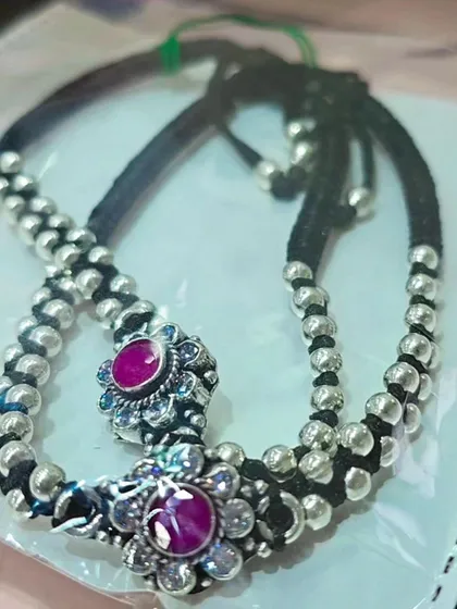A traditional black thread silver payal (anklet) with beautiful oxidized silver details and a pop of pink.