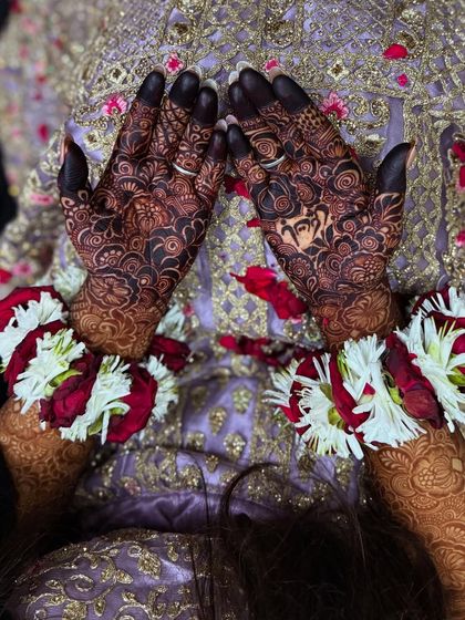 A beautiful photo of a bride's hands, showcasing her dark henna and floral jewelry.