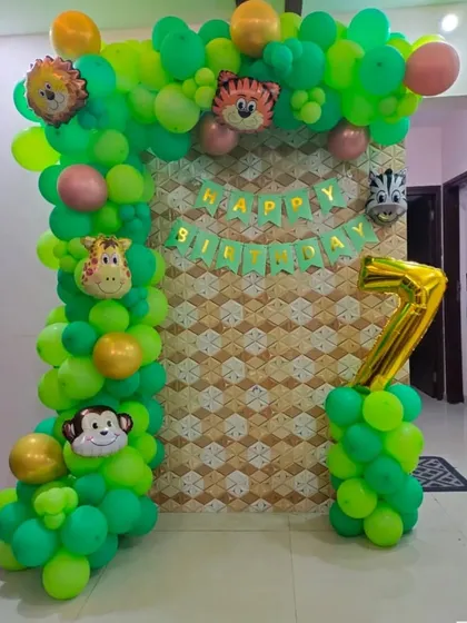 A compact jungle theme balloon arrangement for a 7th birthday. This decor is perfect for smaller spaces, featuring a green balloon pillar with animal faces and a large number '7' foil balloon.
