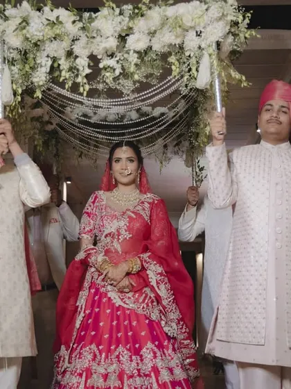 The bride makes her entrance under a beautiful 'phoolon ki chadar' made of white flowers and pearl strings. This traditional and elegant canopy adds a sense of grace and sanctity to her walk down the aisle.