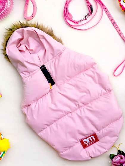 Another view of the pink puffer jacket for dogs, styled as a flatlay with various toys and accessories. The composition is fun, colorful, and appealing to pet owners.