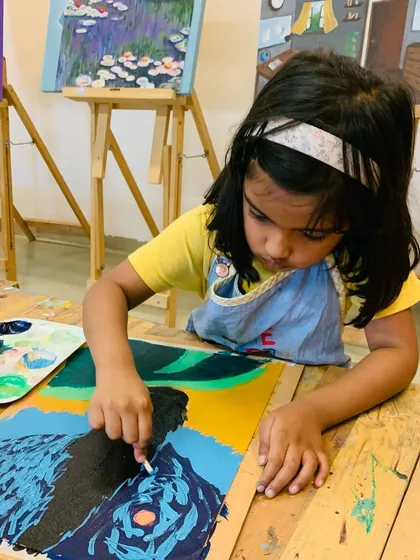 A young girl adds white highlights to her Van Gogh-inspired painting, capturing the effect of moonlight.