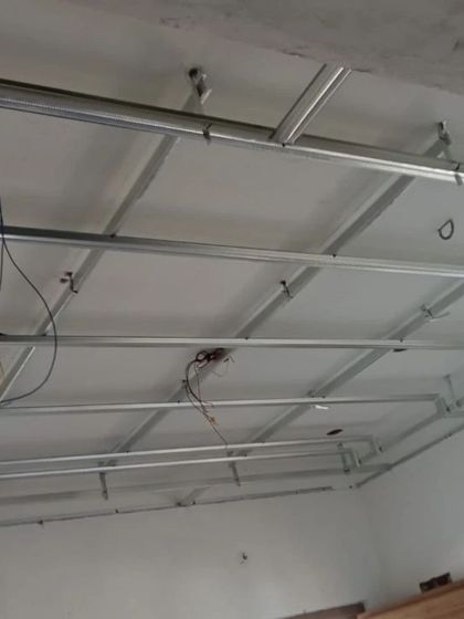 The metal framework for a false ceiling being installed. This is the essential first step before the gypsum boards are fixed.
