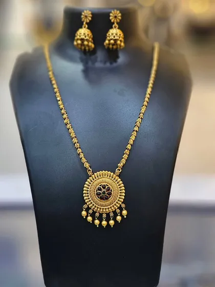A simple yet elegant necklace with a circular pendant and matching jhumkas.
