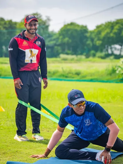 Assisting a player with a resistance band stretch. Individual attention is crucial, even in a team setting, to address specific needs.