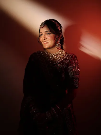 Another beautiful portrait of the smiling bride. This image clearly shows the defined yet natural eye makeup and the perfect shade of lipstick chosen to match her royal velvet lehenga.