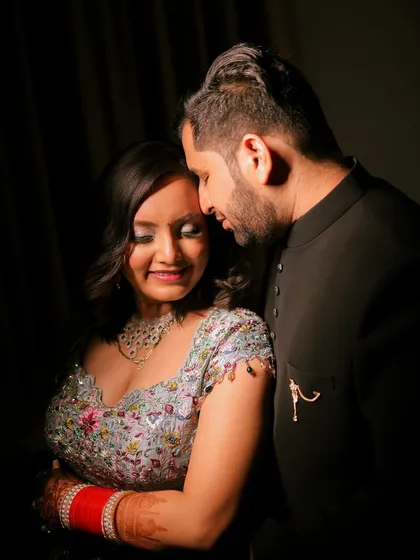 A soft and romantic close-up portrait. The couple shares a quiet moment, their eyes closed, lost in their affection for one another. The lighting is focused on them, creating a moody and intimate atmosphere that feels very personal.