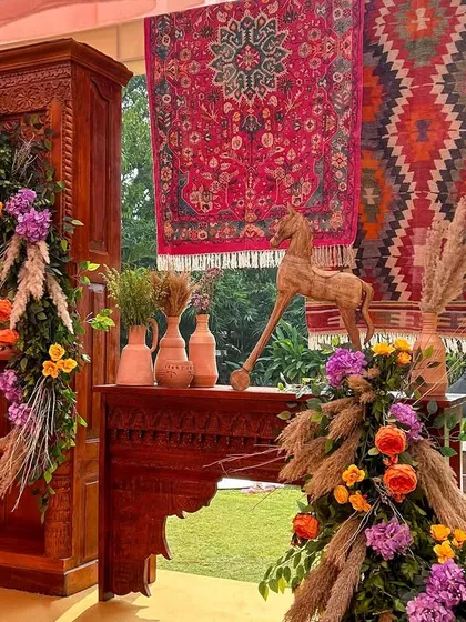 Detailed view of the carved wooden cabinets and rich textiles used as backdrops, layered with floral and pampas grass arrangements for a lush, opulent feel.