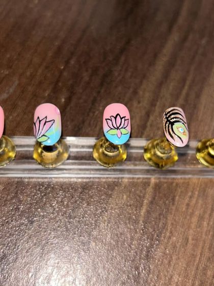 Another view of the hand-painted lotus and peacock feather nails. The blend of pink, blue, and green gives this set a vibrant and artistic feel.